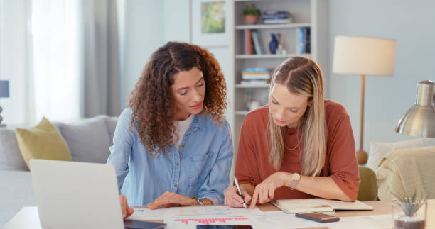 istock Startup, collaboration and women with paperwork in home office, working on business idea. Teamwork, partner and people with laptop work on documents, infographics and analytics writing  project notes 1437684518