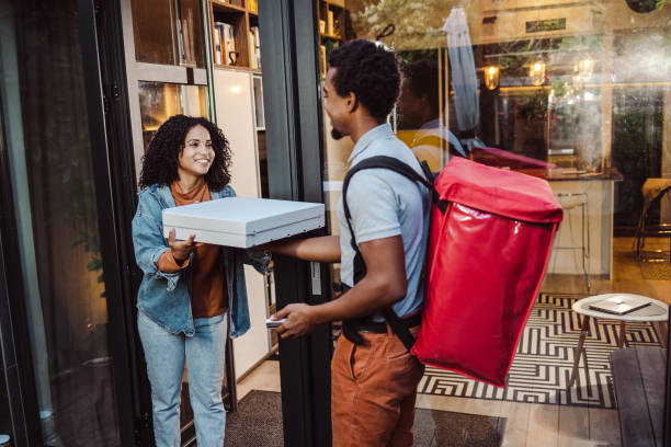 Pizza delivery man giving pizza to a woman stock photo