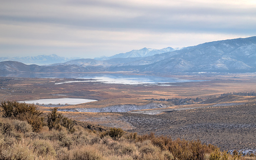 A wide vista of Nevada's Washoe Lake and Washoe Valley landscape with snow-capped Sierra Nevada mountain peaks.
