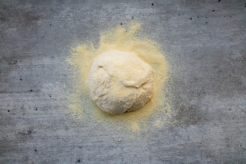 Risen or proved yeast dough for bread or pizza on a floured on concrete surface.