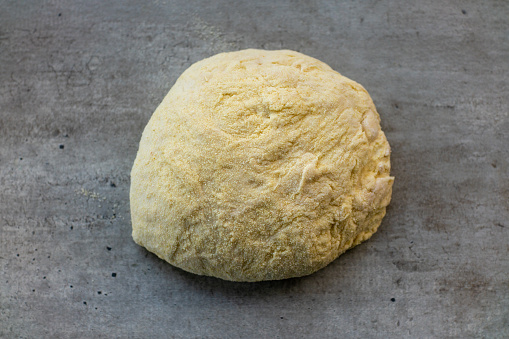 Risen or proved yeast dough for bread or pizza on a floured on concrete surface.