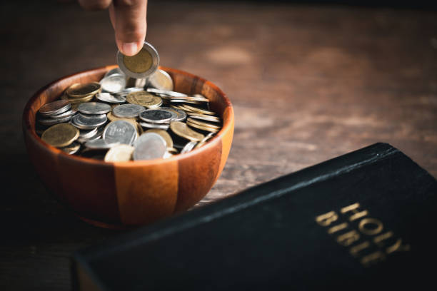 istock One tenth or tithe is basis on which Bible teaches us to give one tenth of first fruit to God. coins with Holy Bible. Biblical concept of Christian offering, generosity, and giving tithes in church. 1437689046