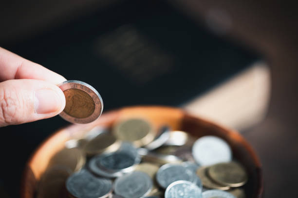 istock One tenth or tithe is basis on which Bible teaches us to give one tenth of first fruit to God. coins with Holy Bible. Biblical concept of Christian offering, generosity, and giving tithes in church. 1437689169