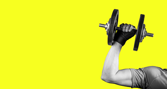 Hand with barbell banner, bright yellow background with copy space. High quality photo