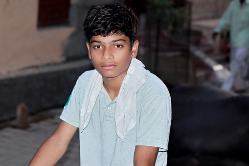 Indian teenage boy standing in street at night.