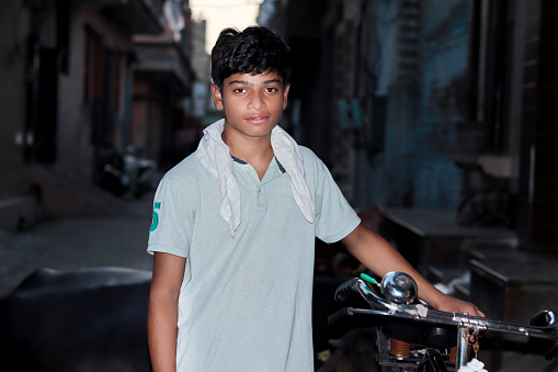 Teenage boy of Indian ethnicity standing with cycle.