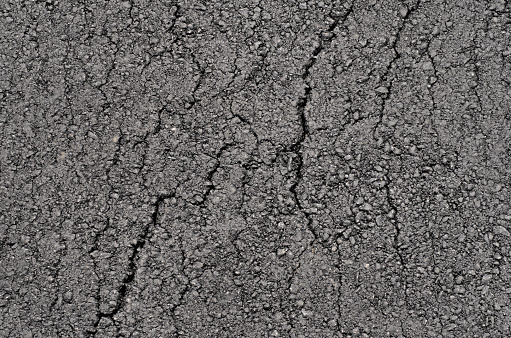 Surface of new clean cracked asphalt. Tarmac grey grainy road texture or background. Top view.