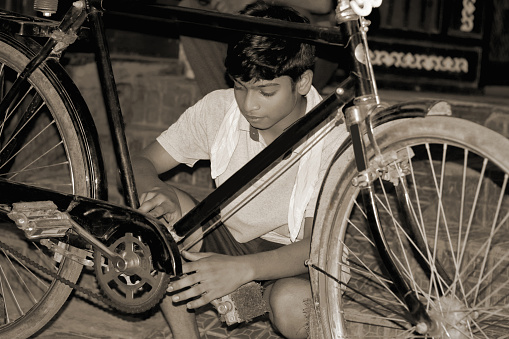 Indian teenage boy repairing cycle as labor.