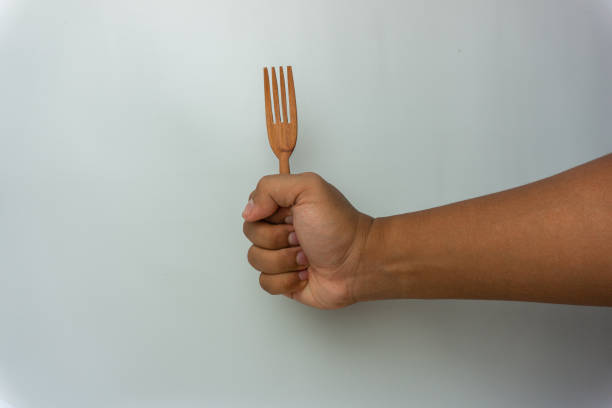istock Hand holding wooden spoon and fork isolated on white background 1437697894
