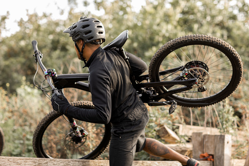 An adventurous black mountain biker enjoying the exercise on an outdoor biking trail