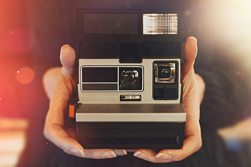 Woman holding retro photo camera with flash.