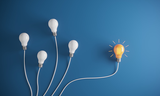 Glowing light bulb between the other light bulbs, flat lay, symbolizing big ideas, innovation concepts. (3d render)