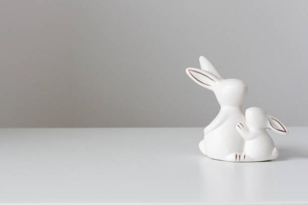 istock Two small ceramic bunnies on a white table and a white background. Festive home decor. Easter concept. 1437703773