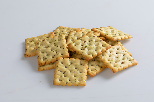 Delicious crispy crackers on baking paper and a wooden table in close up