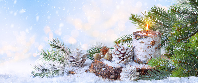 Christmas or New Year Holiday composition with burning candle, pine cones and fir tree. Winter holiday background. Banner