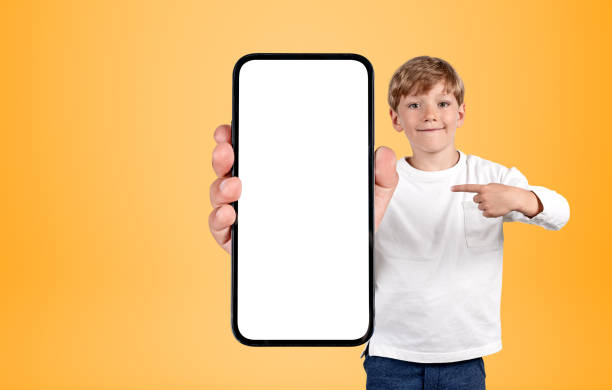 istock Kid finger pointing at phone mockup display on bright background 1437707131