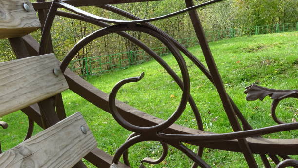 istock Artistic forging on a swing on a green lawn in the autumn square. 1437708073