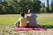istock Back view of young father and his kid sitting close on blanket 1437709952