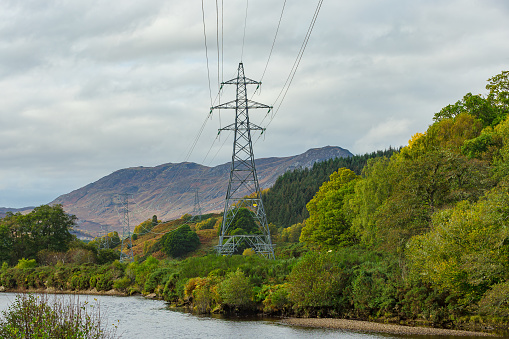 Electricity pylons running beside the River Conon in Strathconon, a remote glen in the Scottish Highlands, providing power to residents and businesses in the glen.  Copy space.  Horizontal.