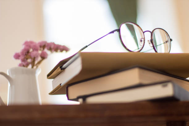 istock Stack of books, eyeglasses and flowers in vase on bedside table 1437713160