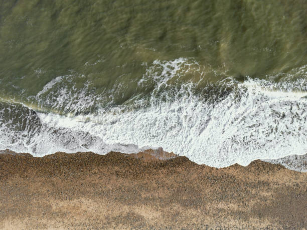 Top down aerial view of waves coming ashore on a shingle beach. Top down aerial view of waves coming ashore on a shingle beach. The shore is part of the Baltic Sea. north sea waves stock pictures, royalty-free photos & images