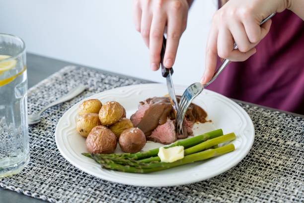 High-angle view of woman hands cutting the served meat on the plate using fork and knife The high-angle view of woman hands cutting the served meat on the plate using fork and knife eating asparagus stock pictures, royalty-free photos & images