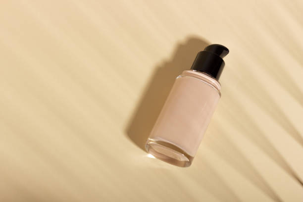istock Foundation in a glass bottle on a background with shadows. Face corrector on beige background with copy space. Packaging mockup with copy space 1437717661