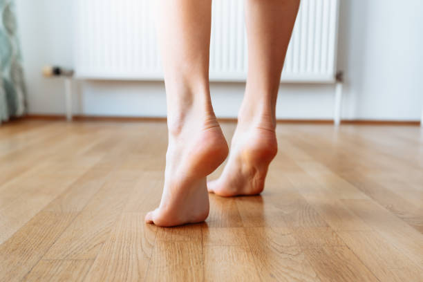 walk barefoot on tiptoe on parquet floor Women's feet walking on warm underfloor heating, tiptoe walking on wooden floor in hardwood living room in modern home home, home floor heating concept, back view background heating radiator tiptoe stock pictures, royalty-free photos & images