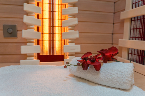 An infrared cabin interior with a white towel and a wonderful flower