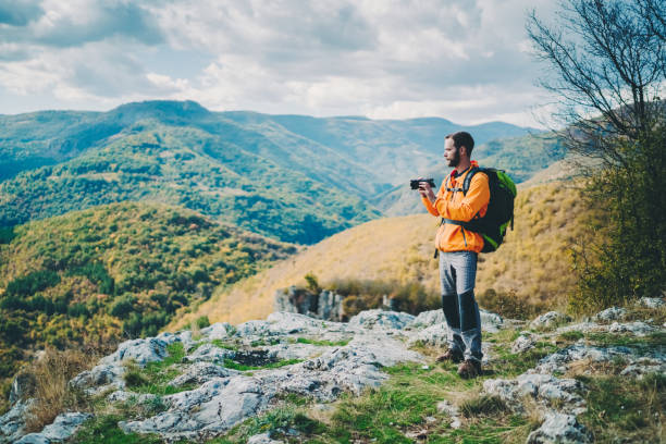 istock Tourist man with camera exploring the mountain and taking photos 1437720399
