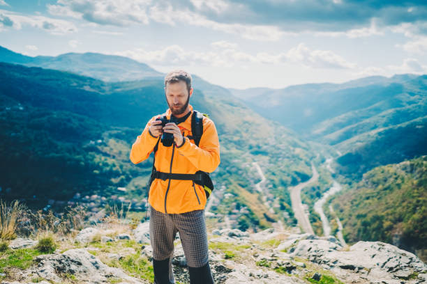 istock Tourist man with camera exploring the mountain and taking photos 1437720439