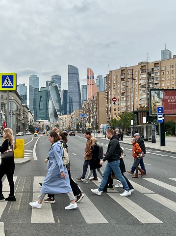 Moscow, Russia - September 11, 2022: People crossing the street, business district with modern skyscrapers on background