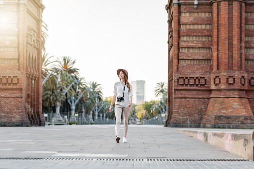 A young stylish female tourist with a camera walking down the Barcelona streets in Spain