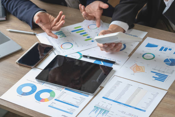 istock Team of business use calculators and graph analysis computer laptop tablets to plan marketing strategies and make profitable investments for the company. 1437730122