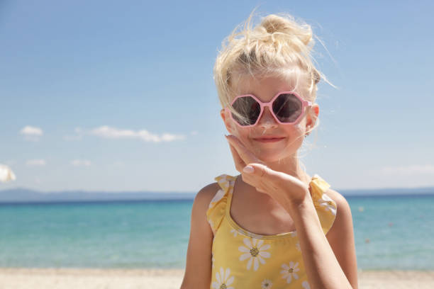 maman appliquant une lotion de protection solaire sur sa mignonne petite fille de 4 ans, soins de la peau pendant les vacances d’été - child caucasian little girls 3 4 years photos et images de collection