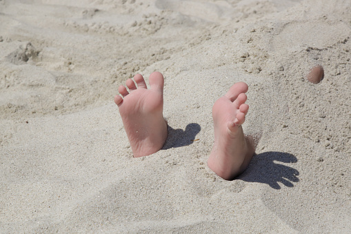 Vacation on tropical beach in Maldives. Woman's legs in the clear ocean water. First person perspective