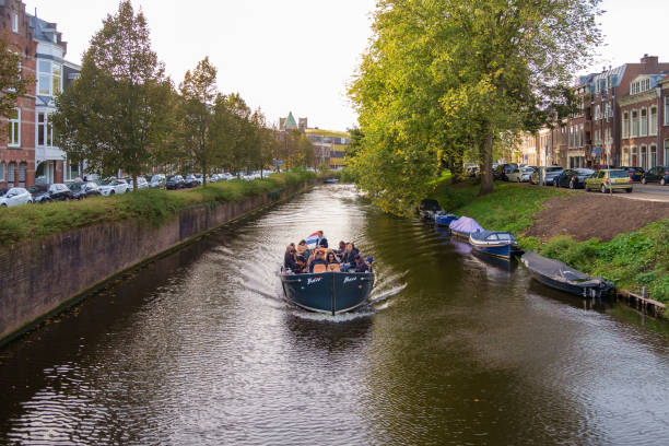 Haarlem, Netherlands - October 22nd 2022: Tourists on a canal boat sail along one of the canals in Haarlem, Netherlands.