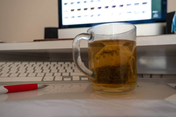 초점이 맞지 않는 키보드와 컴퓨터 앞에서 허브 티에 집중하세요. - mint tea lemon tea leaves glass 뉴스 사진 이미지