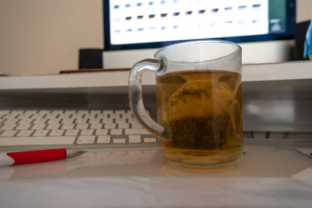 concentre-se no chá de ervas na frente do teclado fora de foco e do computador em casa - mint tea lemon tea leaves glass - fotografias e filmes do acervo