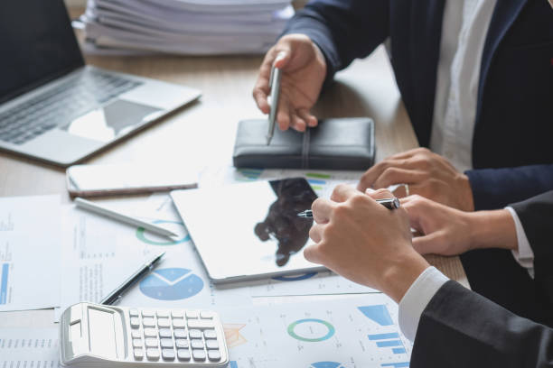 istock Team of business use calculators and graph analysis computer laptop tablets to plan marketing strategies and make profitable investments for the company. 1437734413