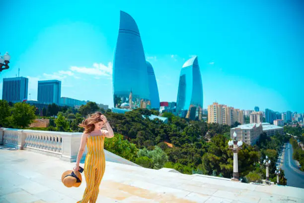 Happy beautiful tourist woman posing in Baku city on the background of Flame Towers