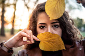 Caucasian girl holding yellow leaves over her face