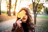 Caucasian girl holding yellow leaf over her face