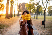 Caucasian girl holding yellow leaves over her face