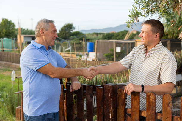 Male neighbors having conversation outdoors, shaking hands