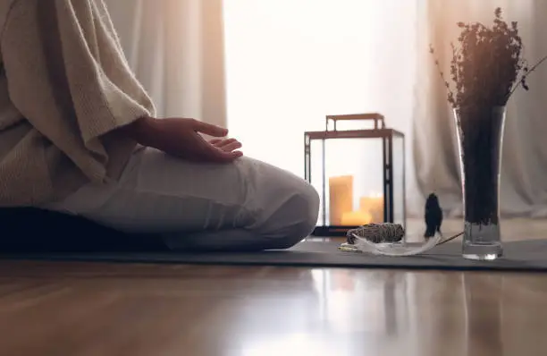 Photo of Open Hands Meditation concept. Woman sitting in lotus position , Candle light, Cozy Atmosphere