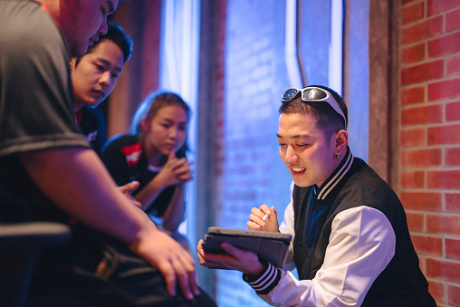 Asian trainer explains strategy to diversity esport gamer team .Stylish neon cyber games arena