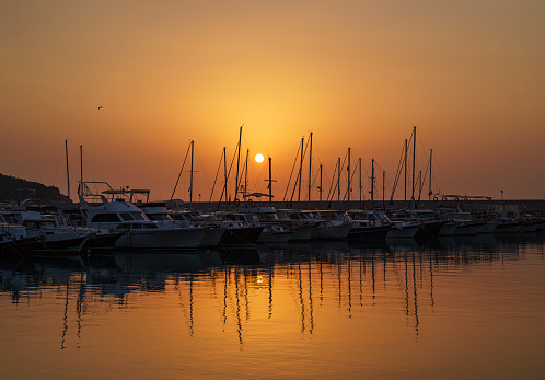Sunrise over boats and sailboats at Antalya Balikci Barinagi (This is a bay of fishing community in Antalya, Turkiye)
