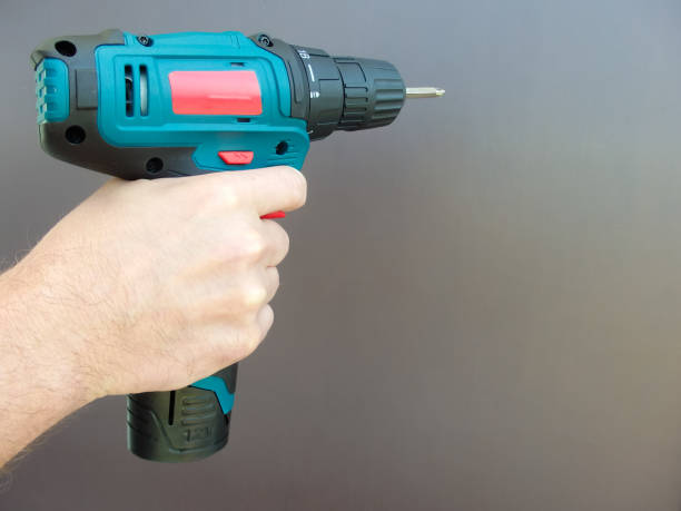 istock Hand 's man with screwdriver. The worker using an electric drill screwdriver, close-up. Concept of repair and construction services. 1437741240