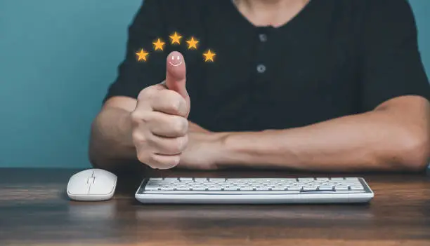 Photo of Young man showing thumbs up and giving positive five stars rating review for client's satisfaction service surveys, Customer evaluation feedback concept.